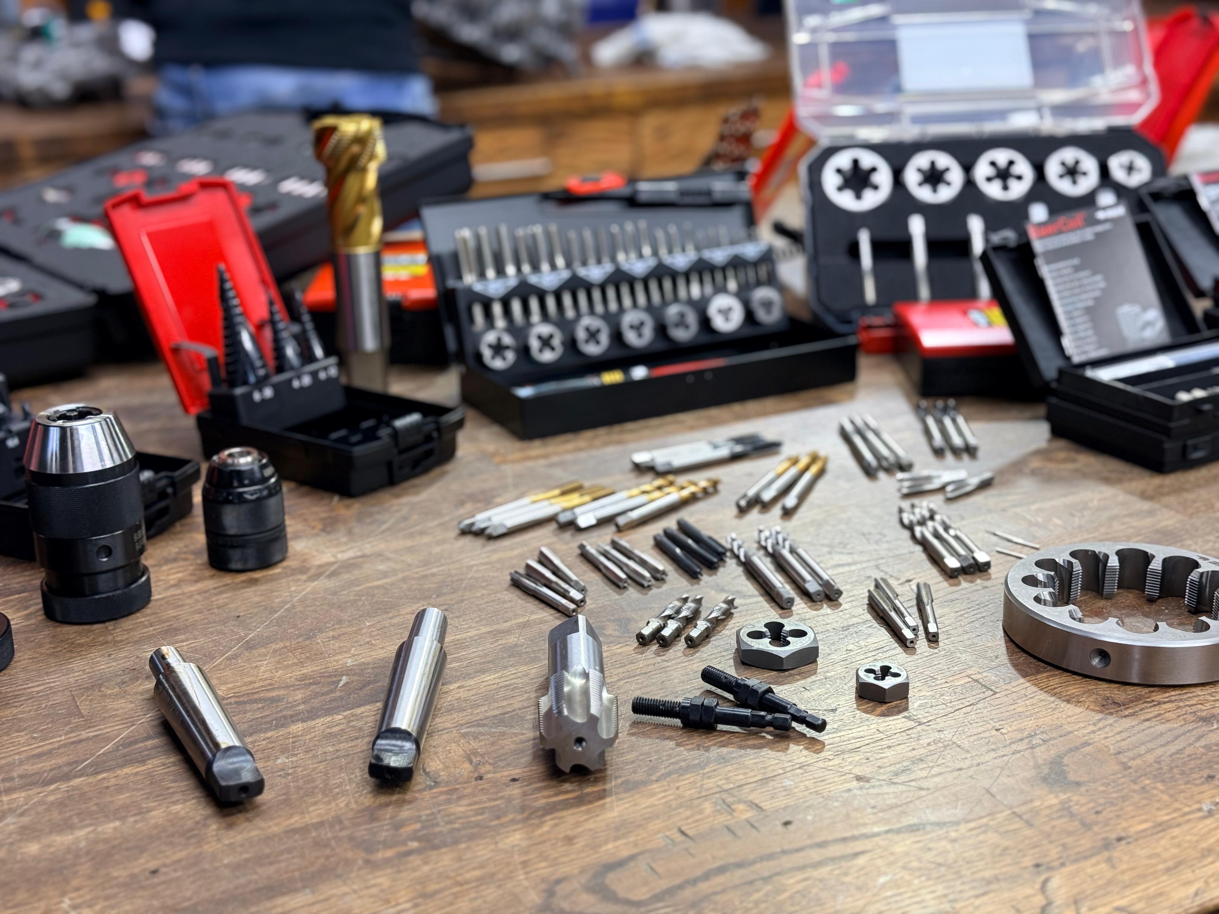 BAER Tools Werkzeuge für Gewindebearbeitung Eine Auswahl an Werkzeugen zum Bearbeiten von Gewinden von BAER Tools liegt auf einer Werkbank.