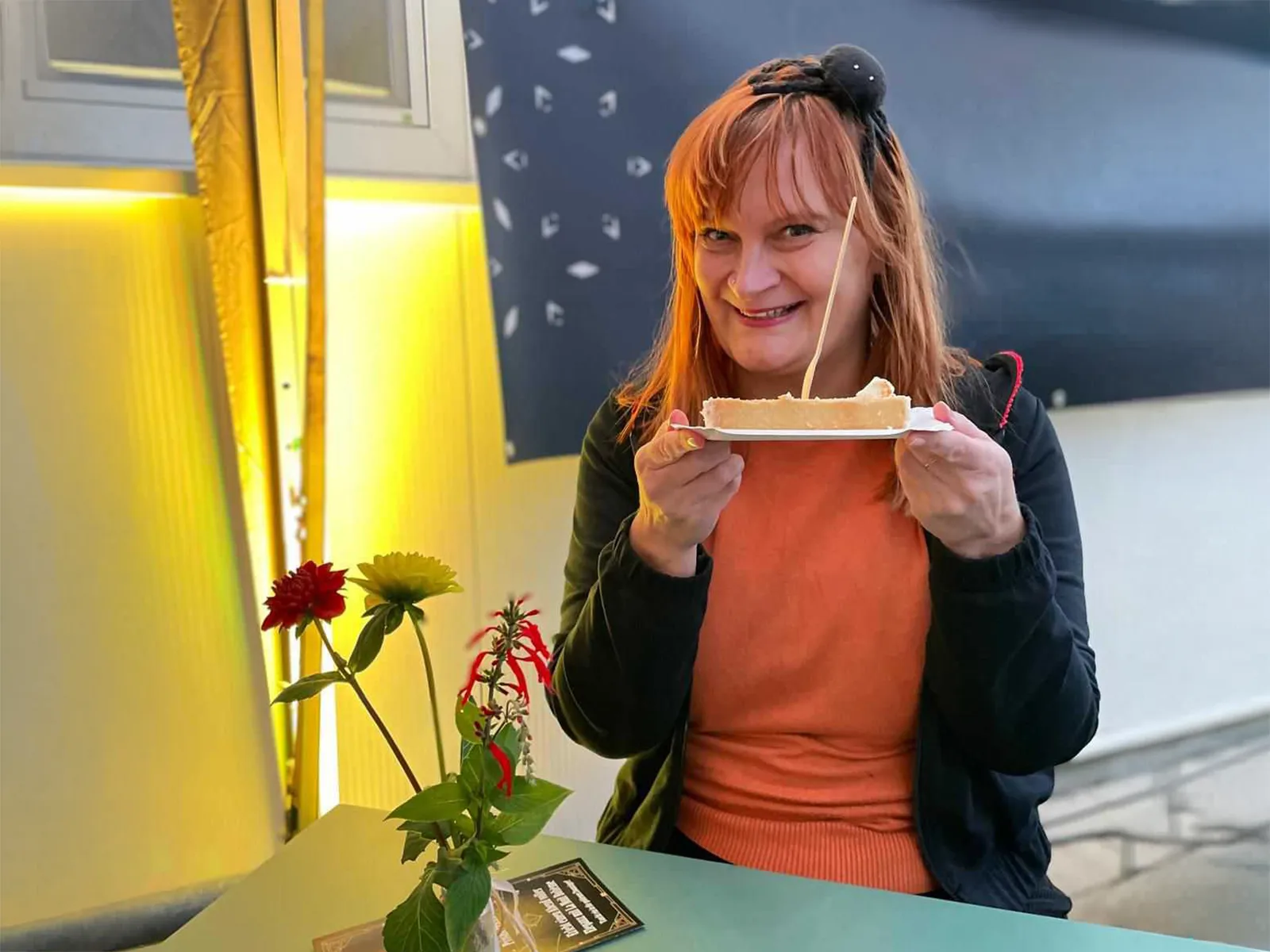 Doreen sitzt mit einem Stück Kuchen am Tisch und feiert 25 Jahre bei ahorn.