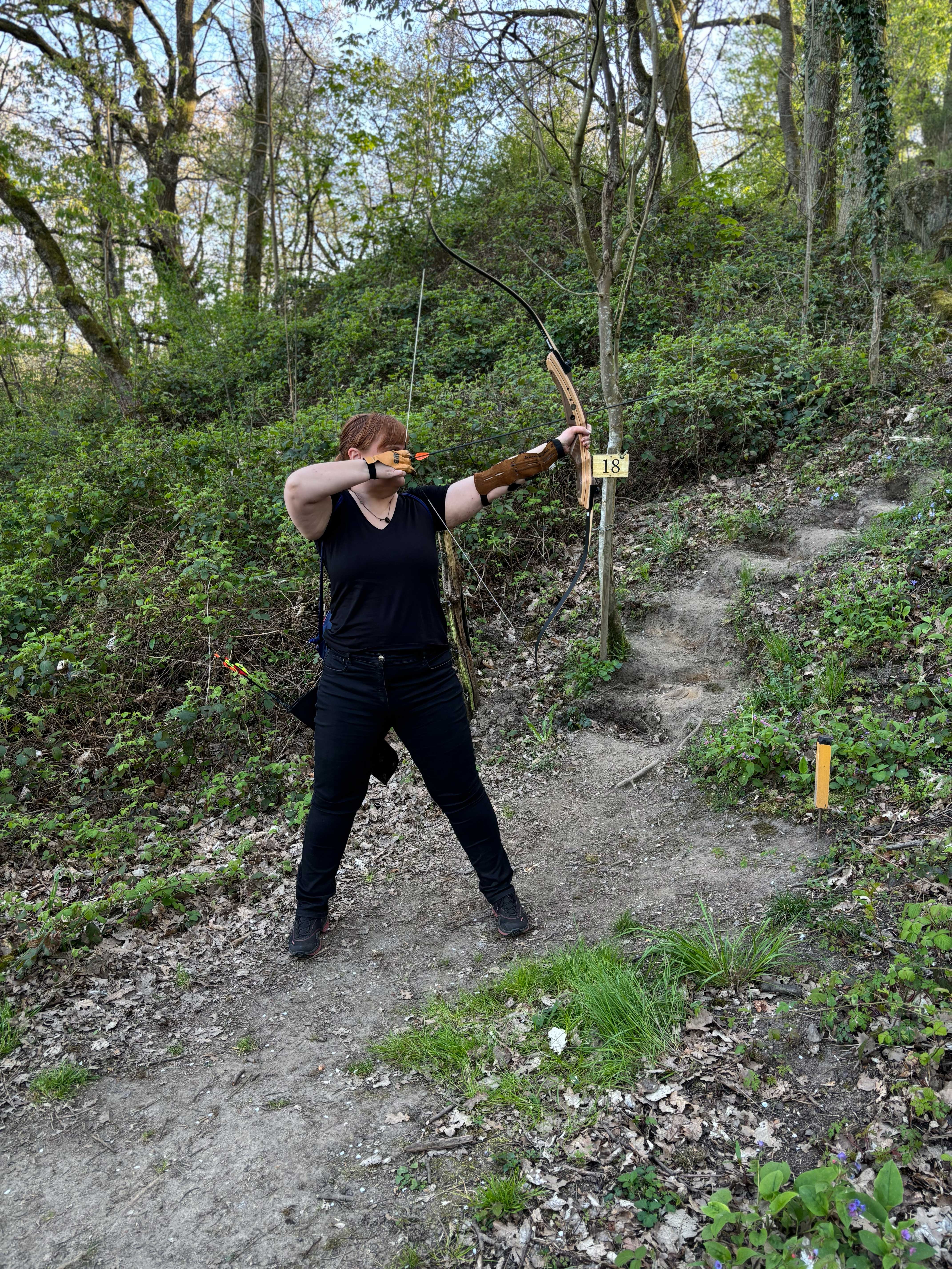 Eine Frau schießt mit Pfeil und Bogen in einem Wald.